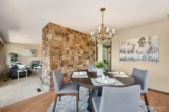 Here’s where things get interesting. The stone from the living room fireplace doesn’t just quit, it wraps cleanly into the dining room, tying the whole space together without a single unnecessary wall. The vintage chandelier adds a layer of elegance that actually works, thanks to the warm wood floors and smart contrast against the soft living room carpet.
