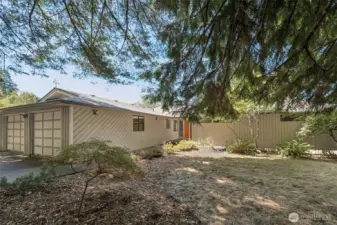 This shot shows off the home’s signature Northwest siding with its diagonal pattern running cleanly along the garage and entry. The two-car garage is fully attached and integrated into the overall design. A mature Japanese maple anchors the front yard with structure and color, while landscape beds and a neat lawn give the exterior a polished, low-fuss finish.