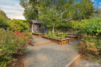 fully fenced garden is terraced and has 5 large raised garden beds.