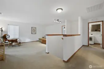 At the top of the stairs is another generous living space, leading to the bedrooms, bathroom, and laundry. Notice the brand new trim throughout, adding a warm wood tone to the fresh white walls.