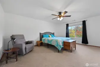 Primary bedroom with backyard views and ceiling fan.