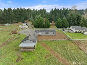 Aerial shot of the backside of the property. Notice the covered area off the shop, in case you want a mini farm.
