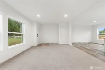 View of the living room shows coat closet and to the right a partial view of the dining room and kitchen.