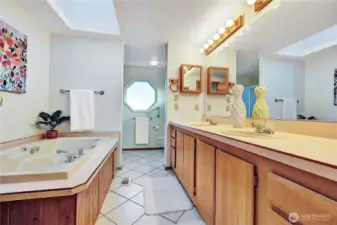 Primary 5-piece bathroom. Large jetted but, separate shower, 2 sinks & toilet. The skylight & octagon window bring plenty of light.