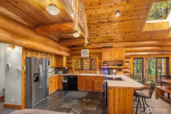 Kitchen offers warm wood cabinetry, generous island seating, and open flow to the living areas ~