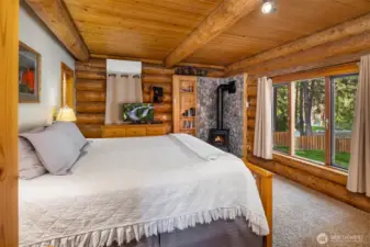 Primary suite with warm log finishes, cozy propane fireplace, and large windows capturing peaceful Wenatchee River views.