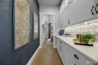 The Butler's pantry with so much extra storage is right between the kitchen and formal dining room. Additional custom features including the cabinet lighting and elegant wall covering.