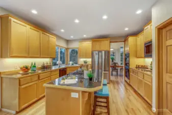 This kitchen is a chef’s dream, featuring expansive counter space, stainless steel appliances, and under-cabinet lighting. Large corner windows provide a view of the backyard, bringing in natural light to brighten the space.