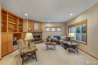 This comfortable family room offers a cozy retreat with a stunning stone fireplace and built-in shelving. Large windows bring in natural light, and the new plush carpeting enhances the room’s comfort.