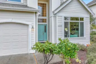 The covered entryway, framed by a grand two-story window, invites you inside. The front door adds a pop of color, complementing the home’s classic exterior. This welcoming entrance sets the tone for the bright, open interior that awaits.