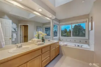 Elegant en-suite bathroom featuring a dual-sink vanity, a large soaking tub, and expansive windows that provide a bright and airy atmosphere.