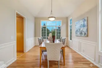 The formal dining room is a showpiece, featuring elegant wainscoting, a vaulted ceiling, and a large picture window overlooking the landscaped backyard. This space is perfect for hosting intimate dinners or festive gatherings.