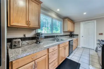 Kitchen with large window with view of side yard. Stainless steal appliances. Granite countertops