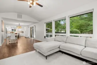Long great-room view toward the kitchen and wall of windows to the deck.