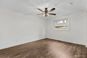 Spacious primary bedroom with ceiling fan and large window.