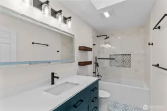 Stylish hall bath with blue vanity, tile tub/shower and patterned niche.