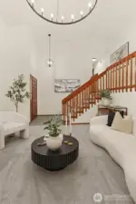 Living room looking to front entry and wide stair case to upper level.