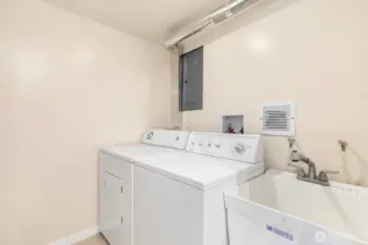 Lower level laundry space with utility sink sits just off kitchen and offers large storage closet.