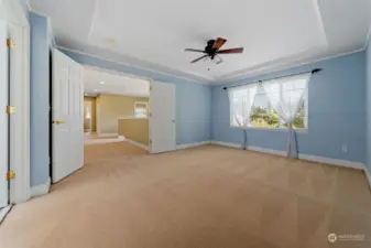 Oversized primary with coffered ceilings, ceiling fan, large window and double doors.