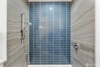 En suite bathroom to primary bedroom. Hansgrohe plumbing fixtures in shower, with separated controls to turn on before stepping in