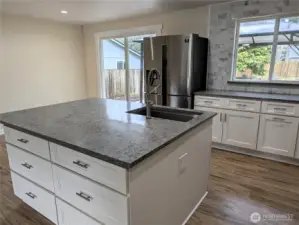 Updated & modernized kitchen with stone counter tops, large island, gas appliances, walk in pantry & pot filling faucet above the cookstove & new LVP flooring. #11823 150th St Ct E, Puyallup, WA 98374