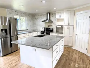 Updated & modernized kitchen with stone counter tops, large island, gas appliances, walk in pantry & pot filling faucet above the cookstove & new LVP flooring. #11823 150th St Ct E, Puyallup, WA 98374