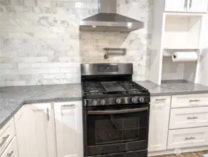 Updated & modernized kitchen with stone counter tops, large island, gas appliances, Walk in pantry & pot filling faucet above the cookstove. #11823 150th St Ct E, Puyallup, WA 98374