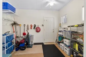 Mudroom or storage room with shelving, storage racks, and exterior door access.