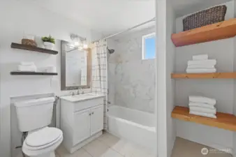 Main floor bathroom updated 2017 with tile surround tub/shower, new vanity with quartz counter, ceramic tiled flooring & new shelves recently built/added for added storage & design