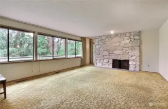 Formal living room with a two sided wood burning fireplace.  The wall of windows provide a view of the private back yard.