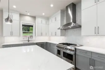 Kitchen features oversized slab quartz island. Stainless steel JennAir appliances and modern lighting!