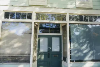 Charming double-door entry framed by transom and display windows—inviting natural light into the main level and showcasing the building’s classic character