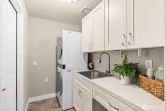 Stacked washer and dryer saves space in the laundry room for folding space on the counters and sink to help rid of stains.