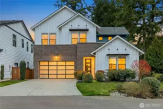 This refined modern farmhouse in the sought-after Winslow Grove neighborhood blends timeless architecture with contemporary design, showcasing crisp white siding, warm brick accents, and inviting interior glow. Thoughtfully landscaped grounds, a welcoming covered entry, and an attached two-car garage create exceptional curb appeal just moments from downtown Winslow, Rotary Park, and the ferry.