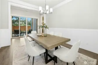 The dedicated dining room offers a clean, modern aesthetic with elegant millwork and contemporary lighting, creating an ideal setting for both everyday meals and special gatherings. Sliding glass doors open to a second patio, enhancing the home’s seamless indoor-outdoor flow and providing additional space for entertaining.
