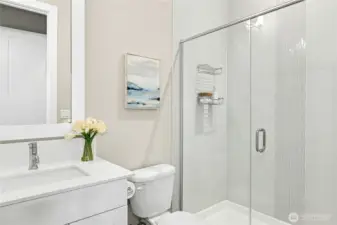 The guest bathroom features a sleek vanity, quartz countertop, and contemporary fixtures that reflect the home’s cohesive modern design. A glass-enclosed shower with clean tile surround adds both style and functionality, creating a comfortable and well-appointed space for visitors.