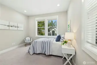 An alternate view of the first secondary bedroom highlights its bright corner placement and comfortable proportions. Generous windows provide abundant natural light while neutral finishes create a versatile space ready to personalize.