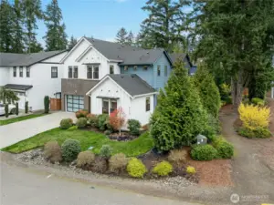 Beautifully landscaped corner homesite in Winslow Grove featuring modern farmhouse architecture with contrasting siding and brick accents. Mature evergreens and manicured grounds provide a private, park-like setting just minutes from downtown Bainbridge Island.