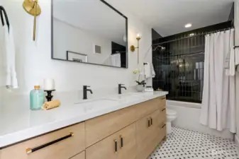 Discover elegance in the main level bathroom, showcasing a double vanity, luxurious finishes, a beautifully tiled tub surround, and modern tiled floors.