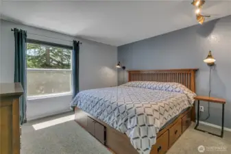 The primary bedroom has a view of the treed area plus custom, built-in shelving in the closet.