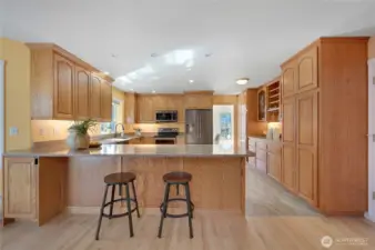 Updated kitchen with stainless appliances, deep sink under a garden window, and extensive oak cabinetry—bright, efficient workspace for home cooks.