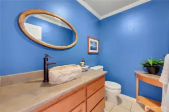 Powder room with bold blue walls, stone vessel sink, and updated faucet—stylish half-bath for guests near front door