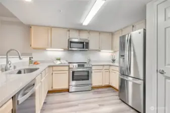Designer kitchen features quartz counters and new SS appliances.