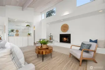The wooden ceilings are carried through in the living room with the clerestory windows above the fireplace wall that bring in so much natural sunlight from the south. There is also a bar or entertaining area to the left.