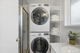Full size, newer washer and dryer in this 3/4 bath, as well as shower semi pictured to the left of washer and dryer, toilet behind the door and sink to the right.  Additionally shelves for added storage needs here.