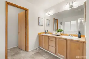 The en-suite bath includes a double-sink vanity with generous counter space and storage, designed for everyday functionality. Vinyl plank flooring adds a durable, easy-care finish to the space. The door to the left leads you to the water closet.