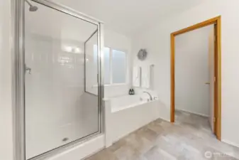 Enjoy a separate soaking tub and glass-enclosed shower, providing both comfort and functionality in a well-laid-out bath. Notice the frosted window for privacy.