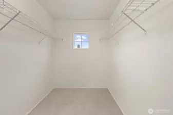 A large walk-in closet with dual hanging systems and a window for natural light offers excellent storage and organization potential.