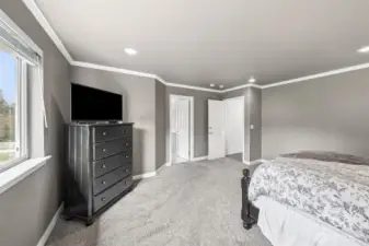 Primary suite boast warm, neutral colors, white crown molding, recessed lighting & plush carpet.