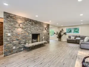 Flooded with light and floor to ceiling stacked stone fireplace in this large family room for big gatherings.
